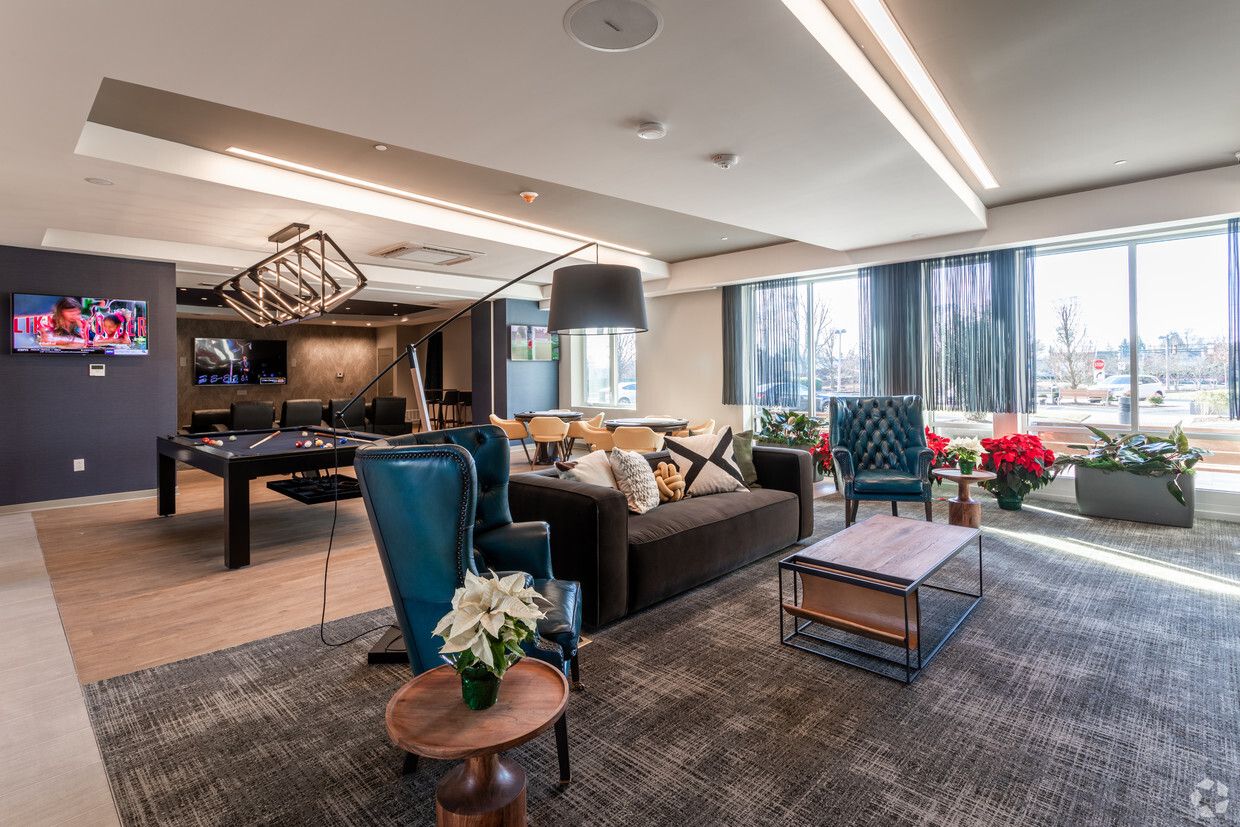A community game room featuring a billiards table, a TV, a seating area, and large windows at The Residences at Bentwood.